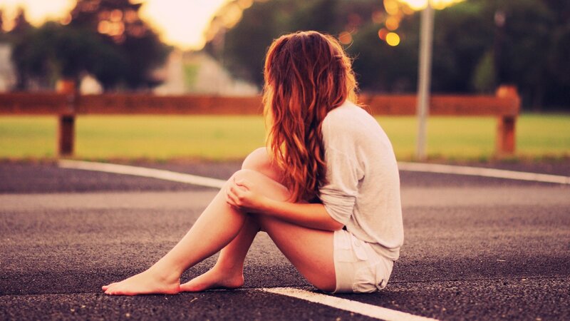 woman sitting on road at sunset