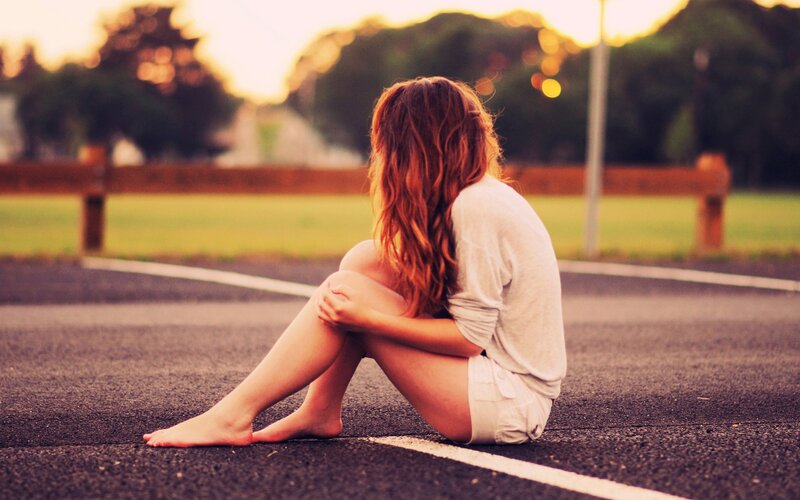 woman sitting on road at sunset