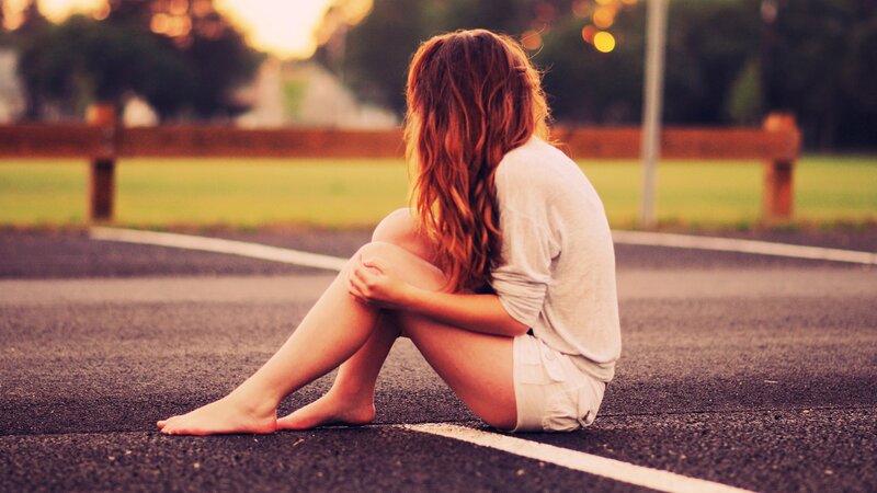 woman sitting on road at sunset