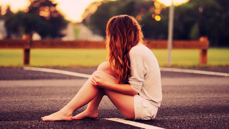 woman sitting on road at sunset
