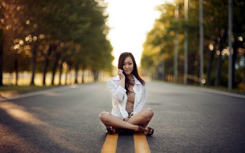 woman sitting on road at sunset