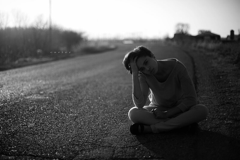 woman sitting on road at sunset
