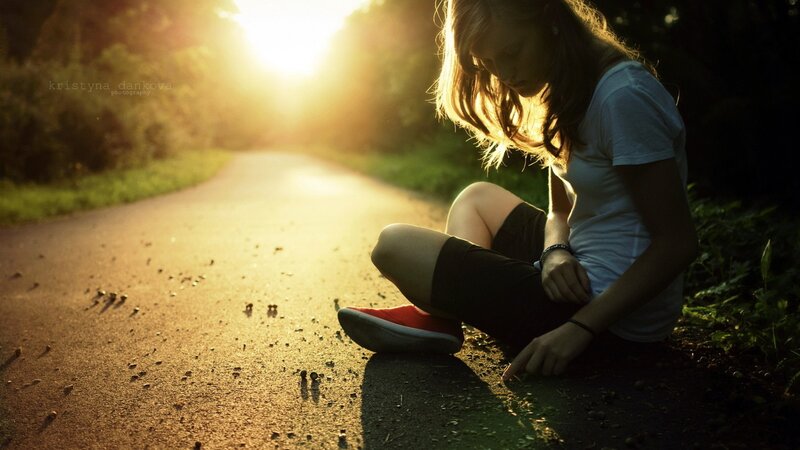 woman sitting on road at sunset