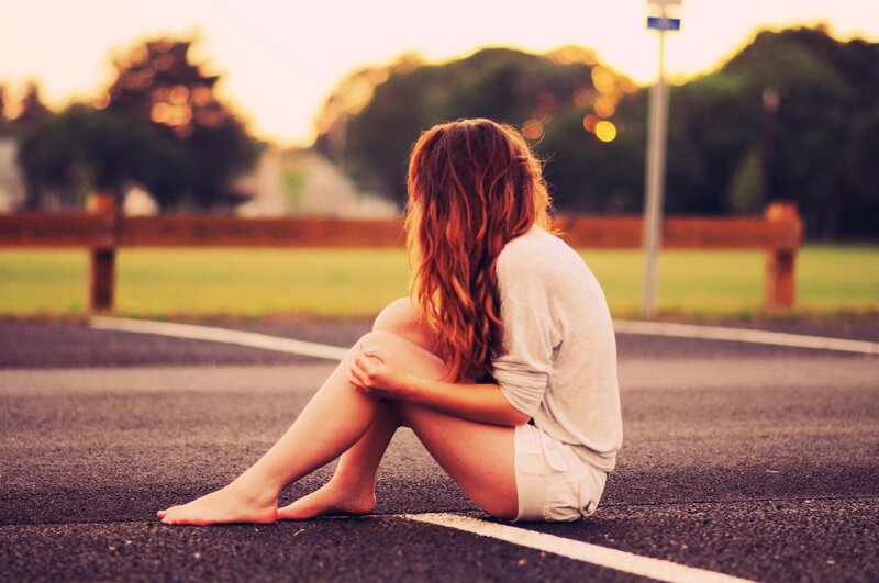 woman sitting on road at sunset