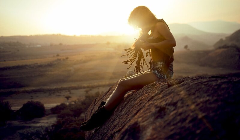 woman sitting on rock at sunset