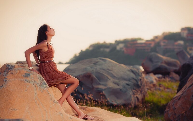 woman sitting on rocks at sunset