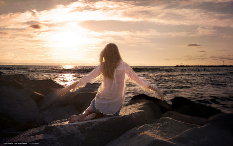 Woman sitting on rocks at sunset