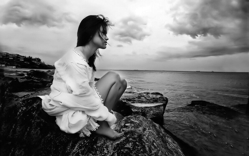 Woman Sitting on Rocks — Black, Dramatic, Photograph