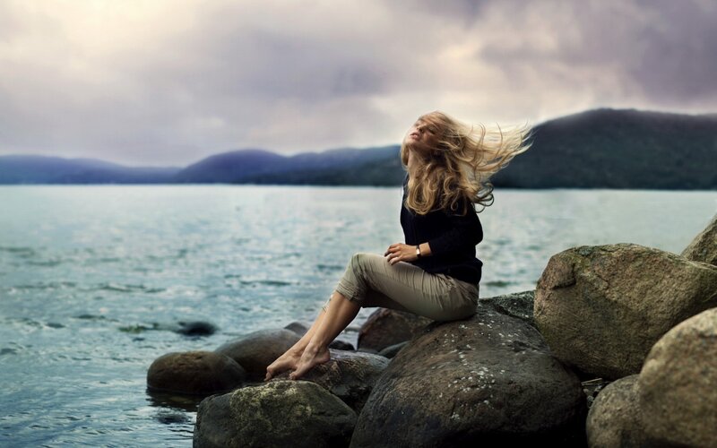 Woman Sitting on Rocks — Blue, Dramatic, Photograph