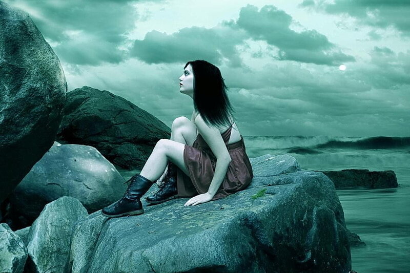woman sitting on rocks by sea