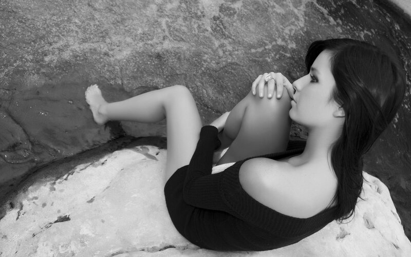 woman sitting on rocks by water