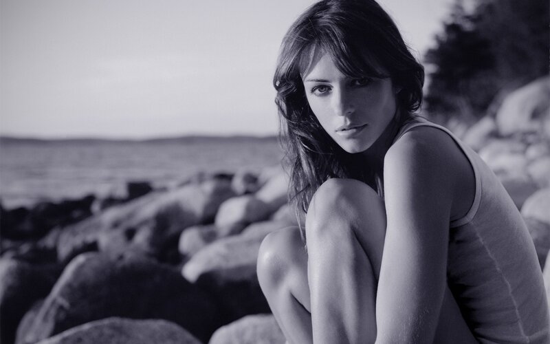 woman sitting on rocks by water