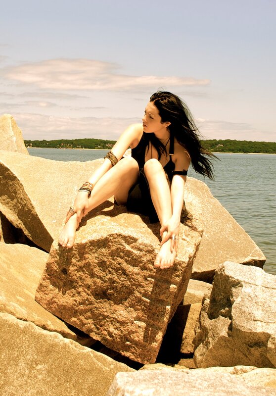woman sitting on rocks by water
