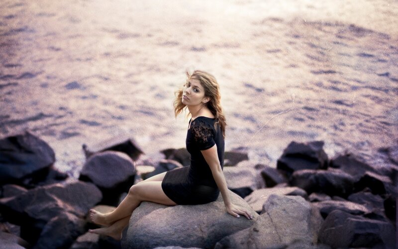 woman sitting on rocks by water