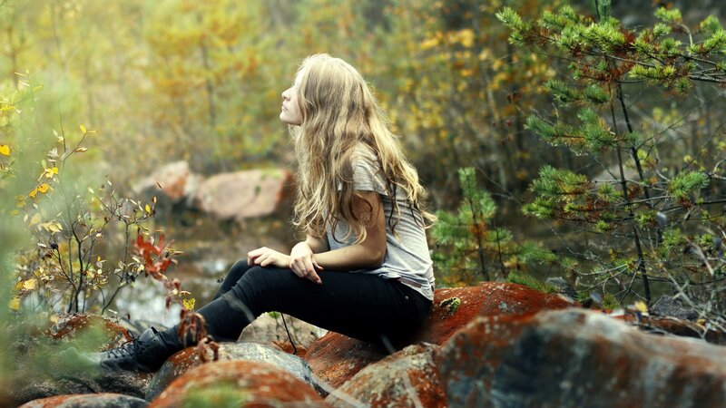 woman sitting on rocks in forest
