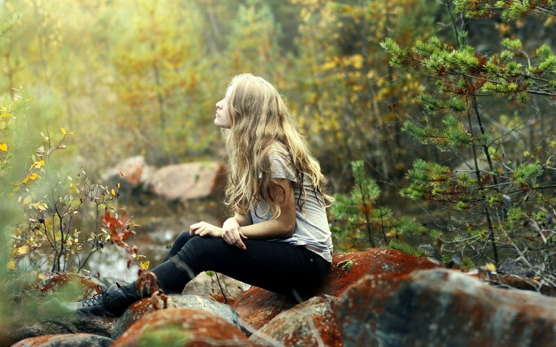 woman sitting on rocks in forest