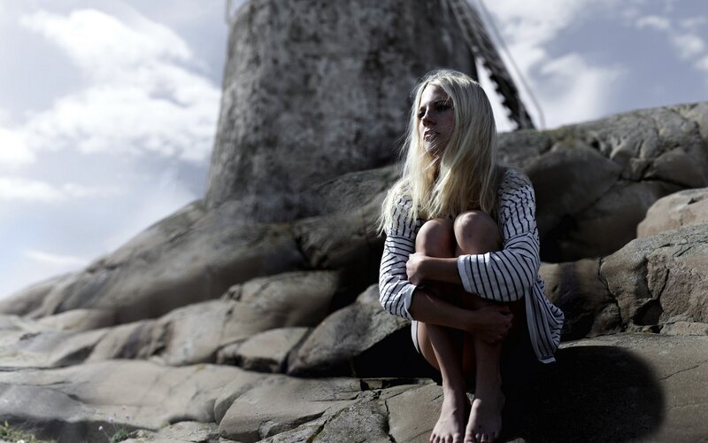 Woman sitting on rocks near windmill