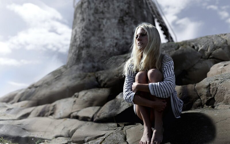 Woman sitting on rocks near windmill