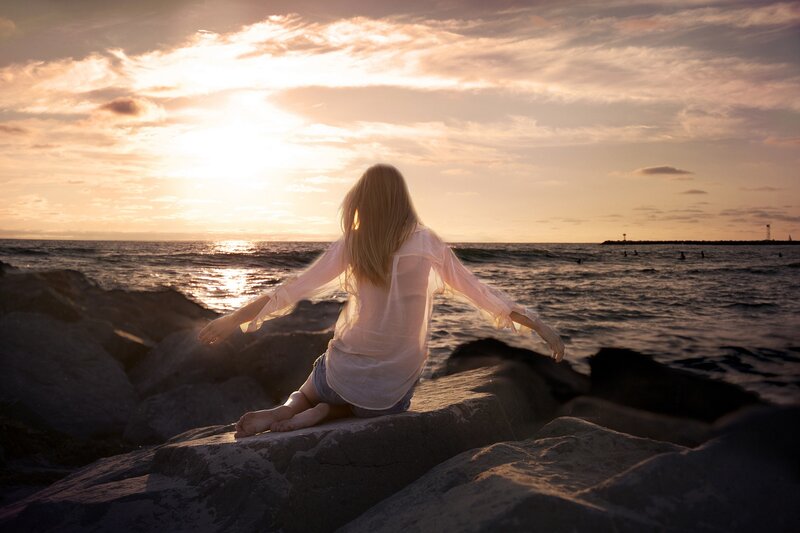 Woman Sitting on Rocks — Orange, Serene, Sunset, Photograph