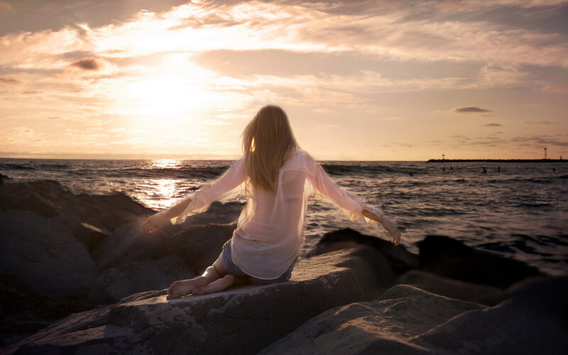 Woman Sitting on Rocks — Orange, Serene