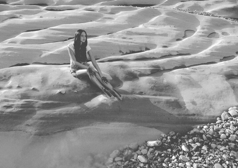 woman sitting on rocky shore
