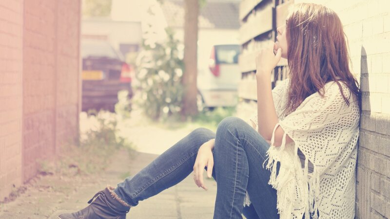 woman sitting on sidewalk