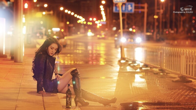 woman sitting on sidewalk at night