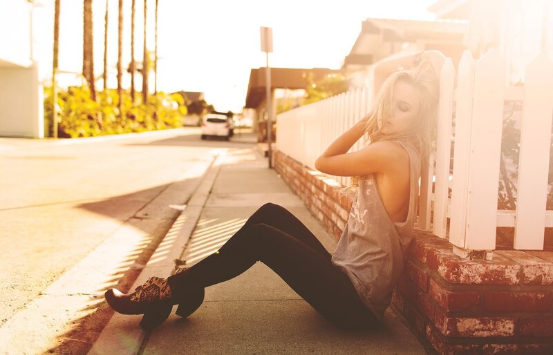 woman sitting on sidewalk at sunset