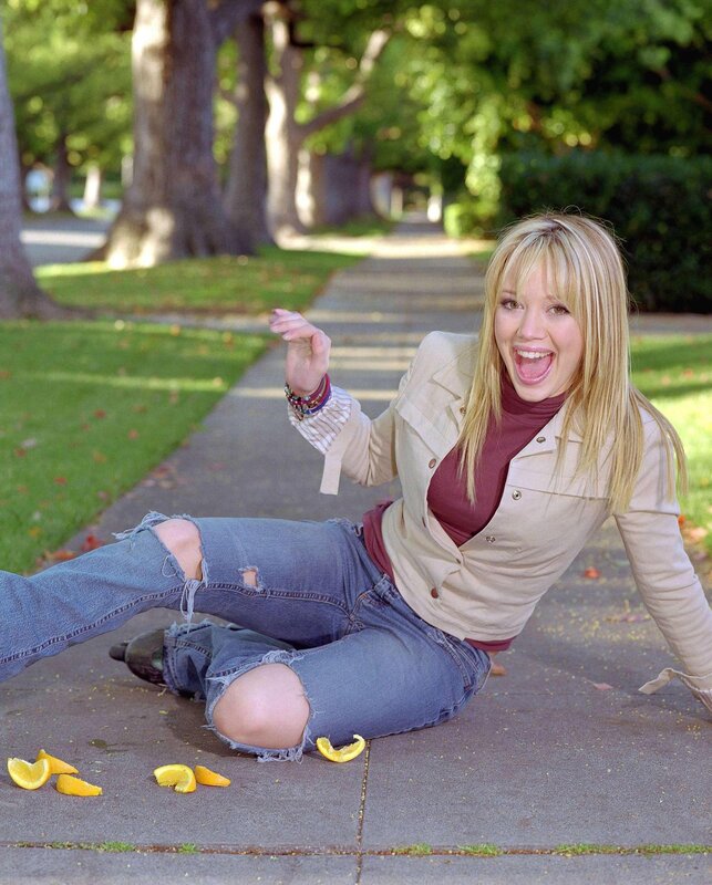 Woman sitting on sidewalk with oranges