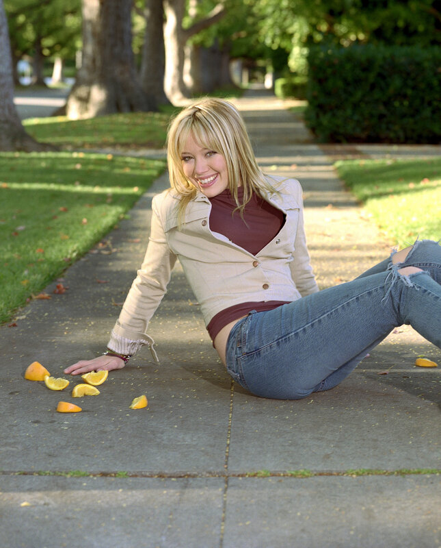 woman sitting on sidewalk with oranges