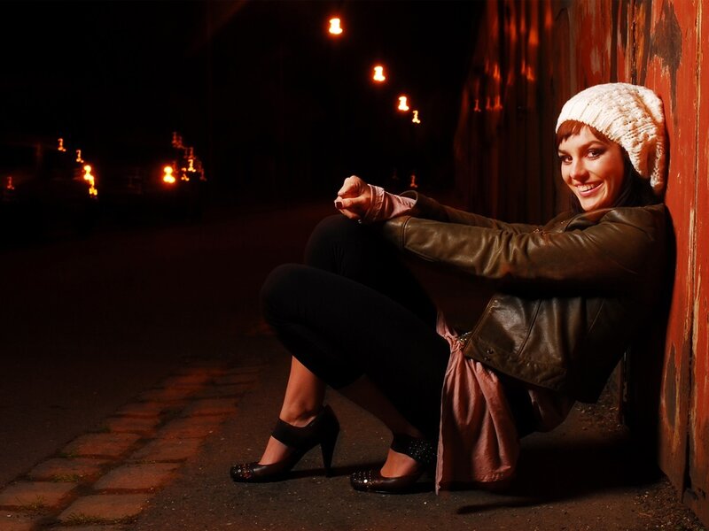 Woman sitting on street at night