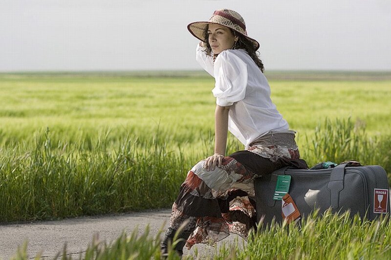 woman sitting on suitcase in field