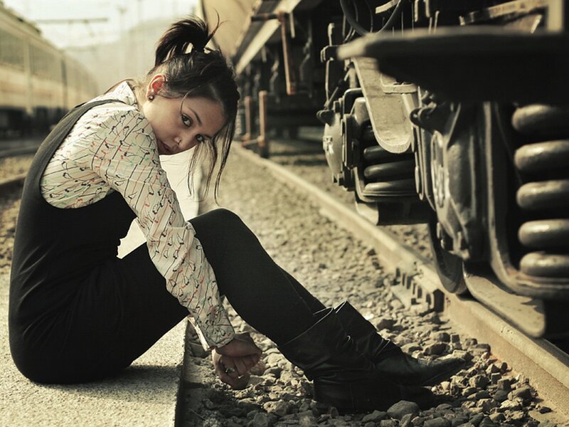 woman sitting on train tracks