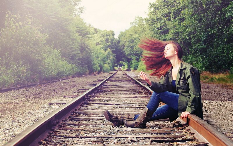 Woman sitting on train tracks