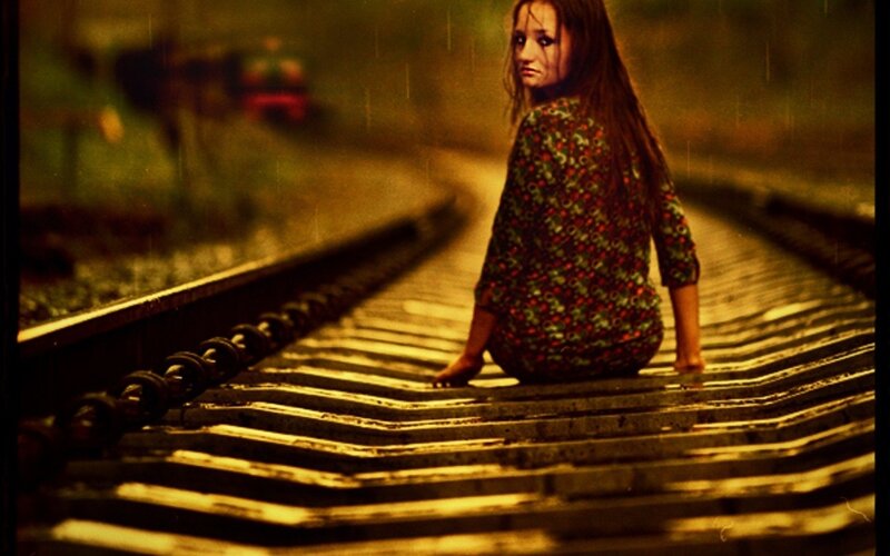 woman sitting on train tracks