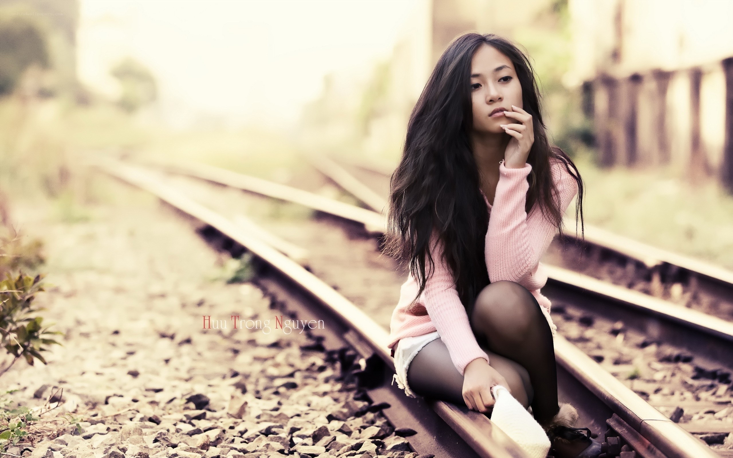 woman sitting on train tracks