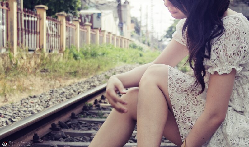 woman sitting on train tracks