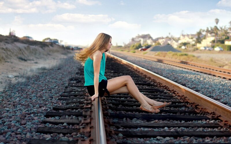 woman sitting on train tracks