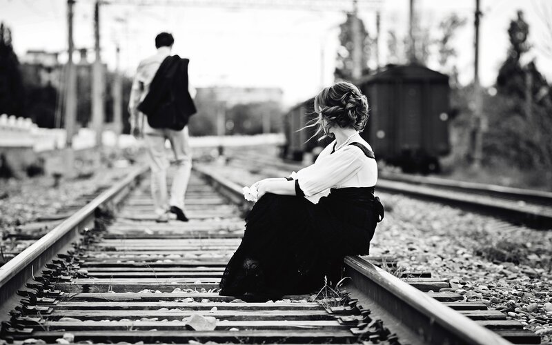 woman sitting on train tracks