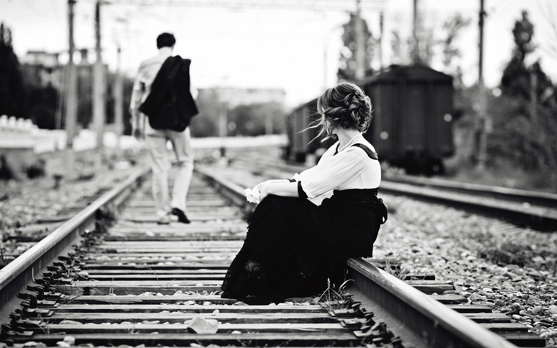 woman sitting on train tracks