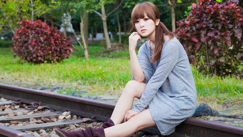 woman sitting on train tracks