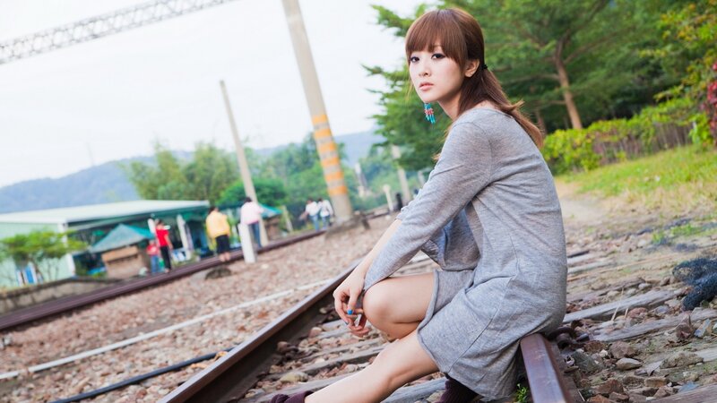 woman sitting on train tracks