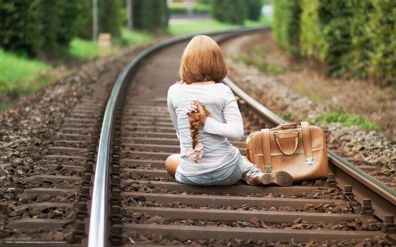 Woman sitting on train tracks