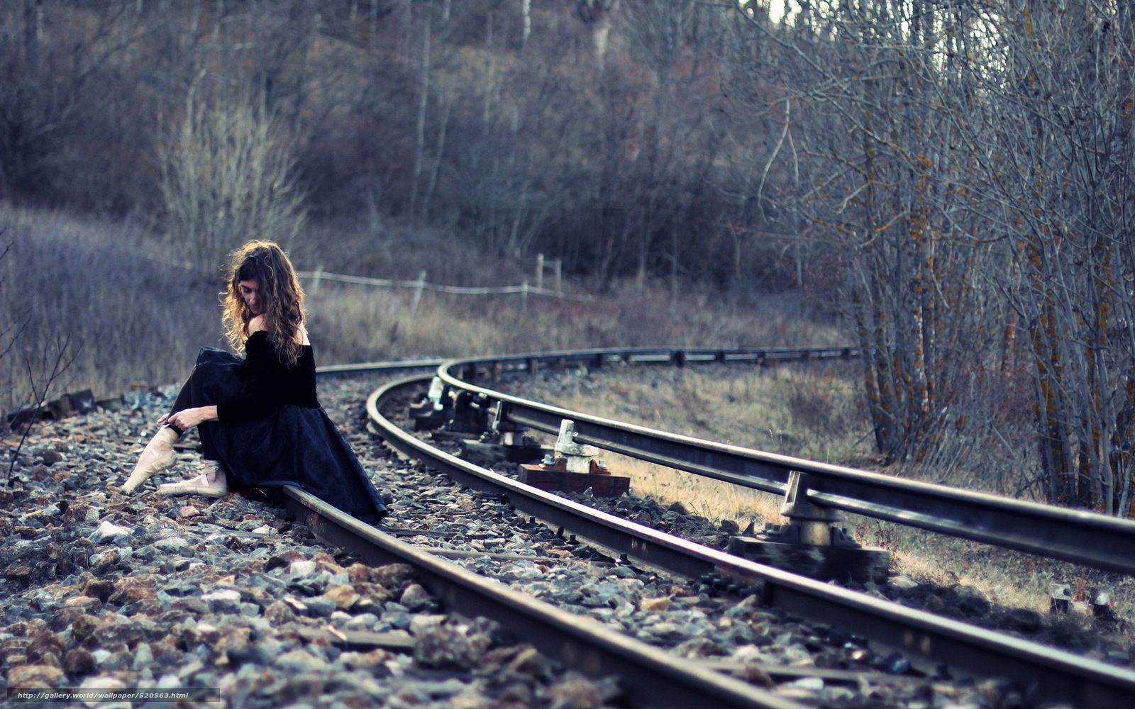 woman sitting on train tracks