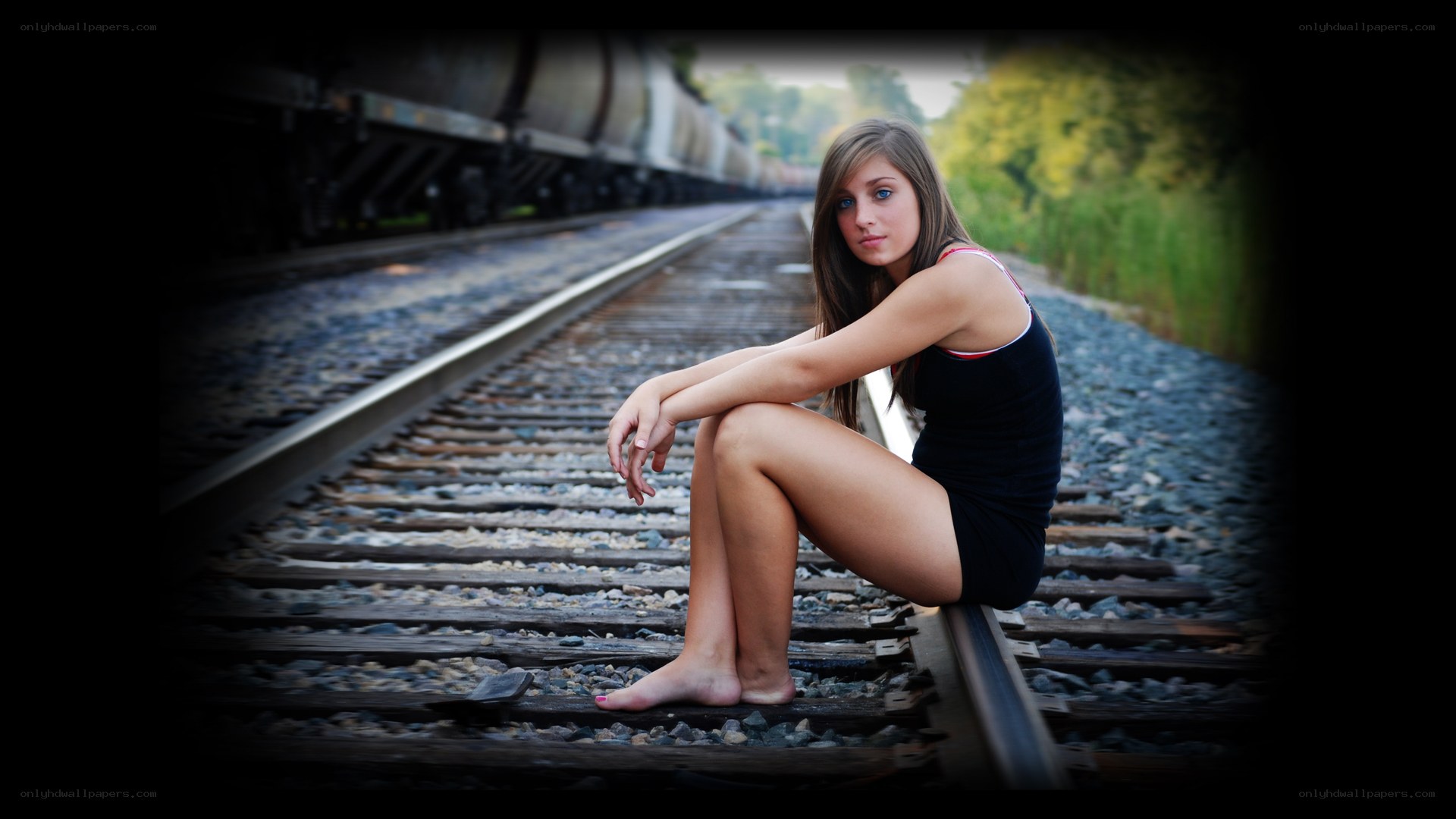 woman sitting on train tracks
