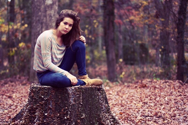 woman sitting on tree stump