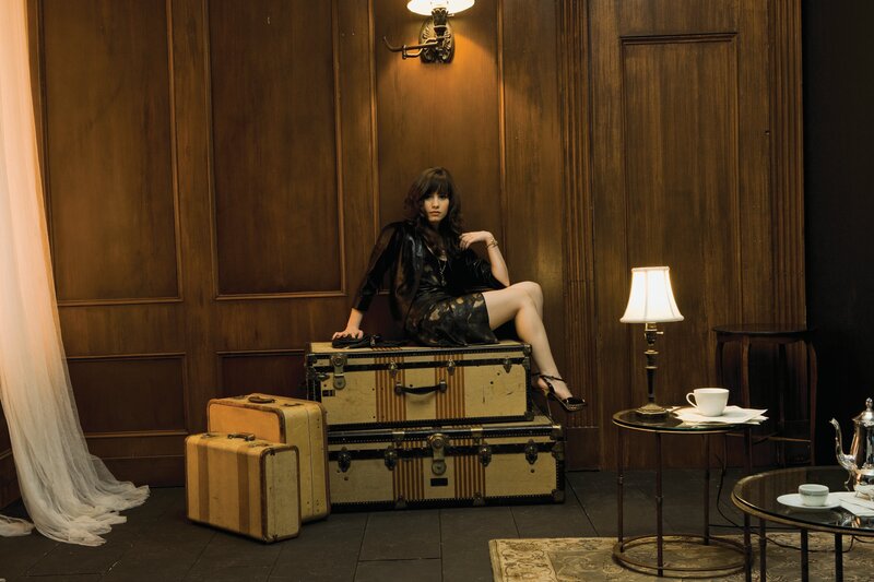 woman sitting on vintage suitcases