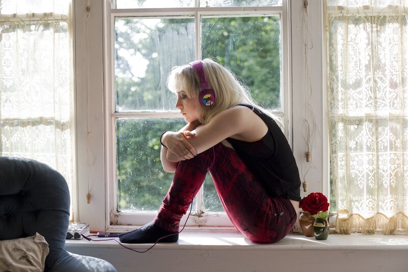 woman sitting on windowsill with headphones