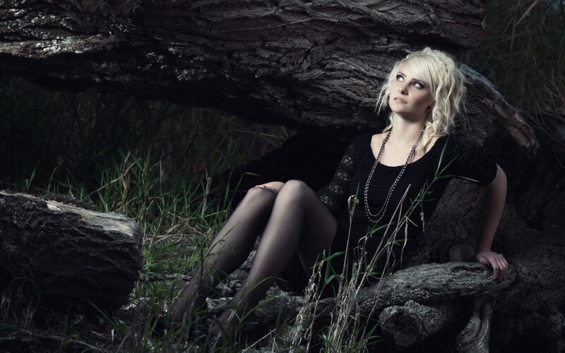 woman sitting under a log