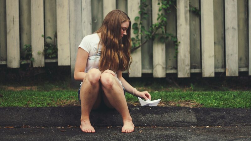woman sitting with paper boat